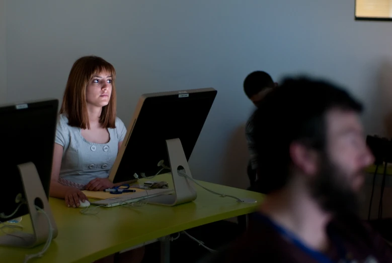 a beautiful young lady sitting in front of three laptops