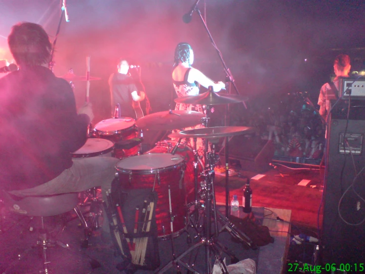 a man is playing drums while another band plays music behind him