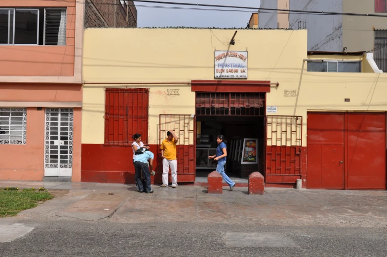 three young people stand outside a building where two children are standing in front of it