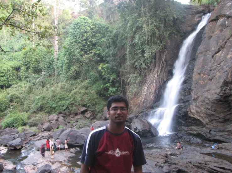 a man standing near a waterfall with a group of people under it