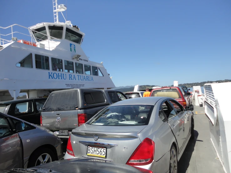 cars parked on the side of a ferry as it approaches another vessel