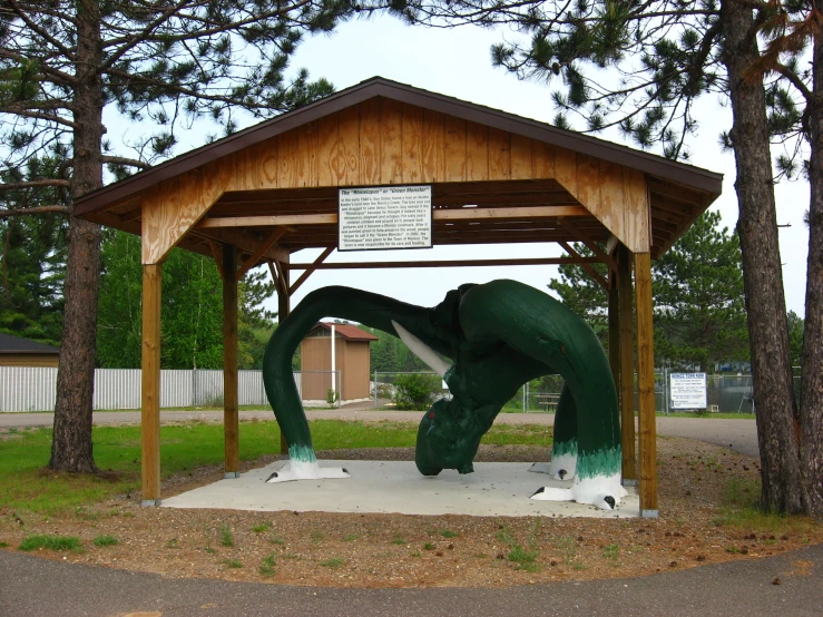 there is a small shelter with a large green elephant