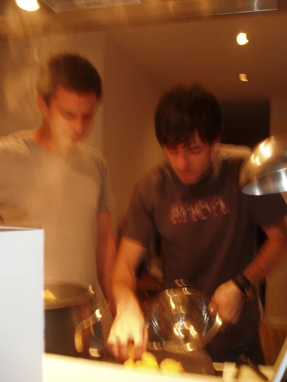 two men standing at a counter preparing food