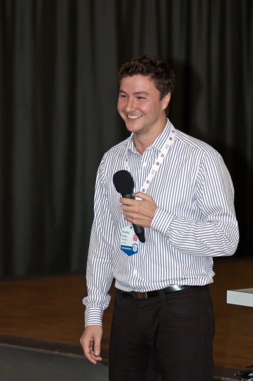 a man standing next to a stage holding a microphone