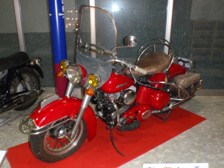 red motorbike on display in glass case at indoor event