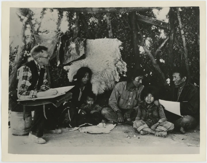 black and white image of men, women and an indian sitting together
