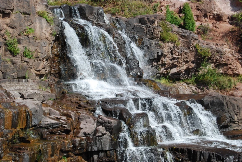 a small waterfall at the top of a rocky mountain