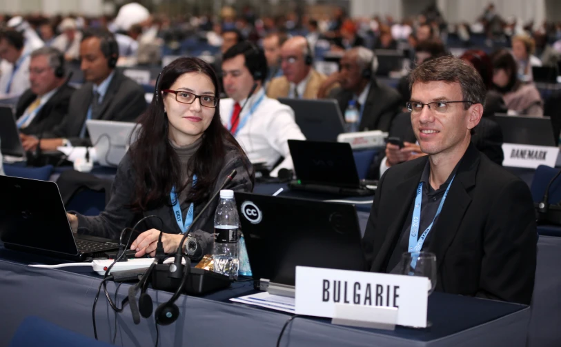 two people sitting at laptops and listening to speakers