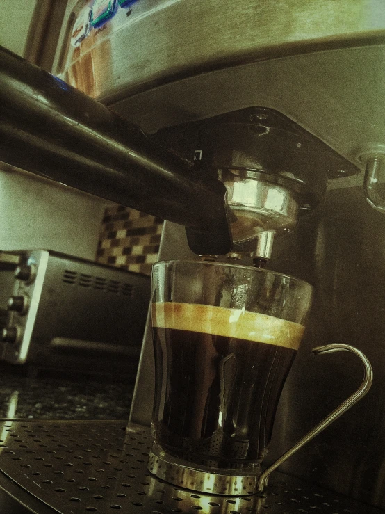 a coffee cup filled with brown liquid in front of an oven