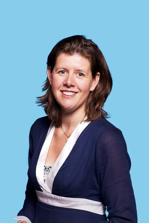 a smiling woman in blue cardigan over white dress