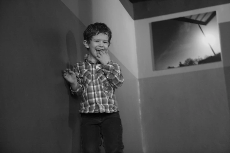 a  posing by the wall with his hand in his mouth