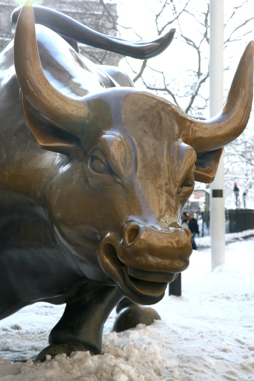 large metal bull sculpture on side of street in snow