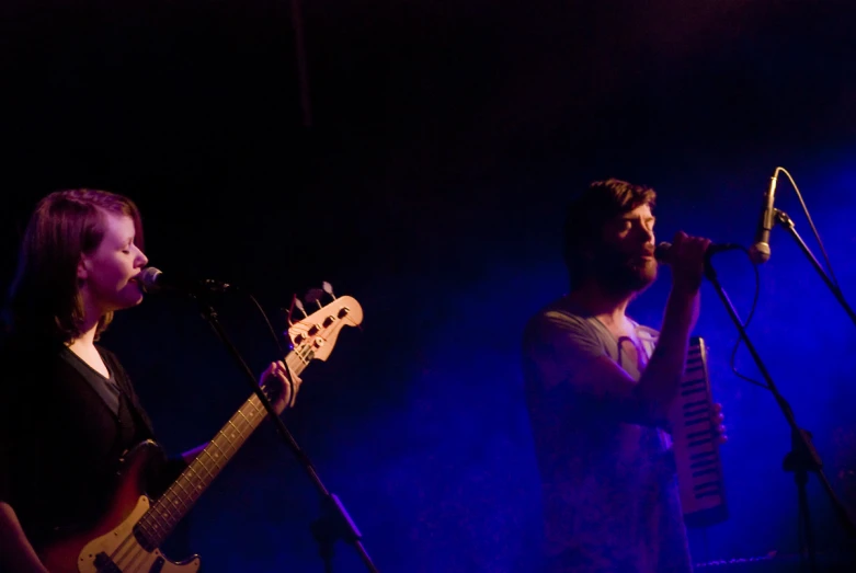 two people are singing at a concert and there is a guitar on the other side of the microphone