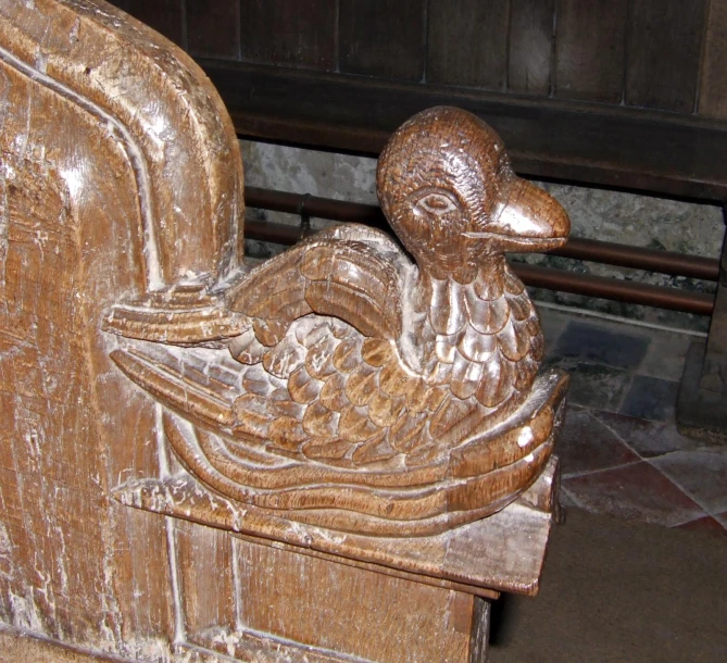 a carved wood bench in a room with a metal rail and wooden floors