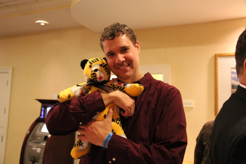 a man holding a small yellow stuffed animal