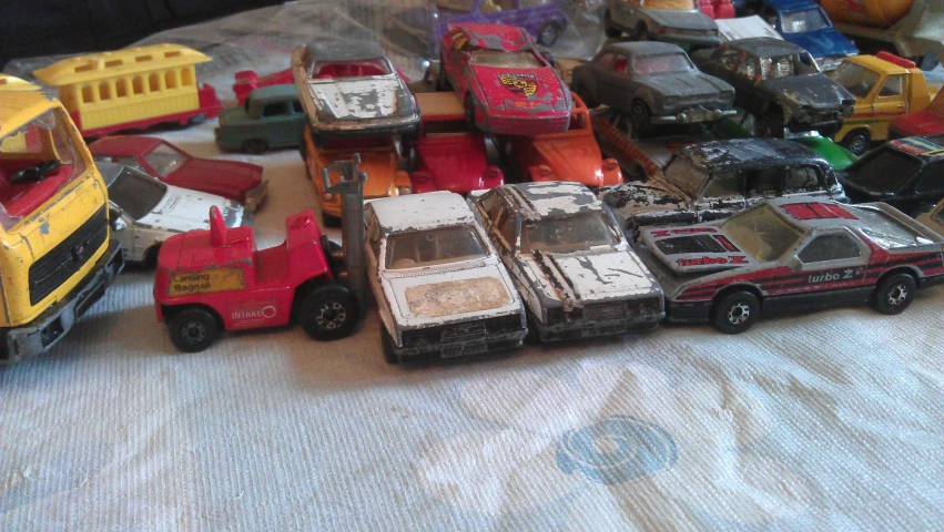 a close up of toy cars in a pile on a bed