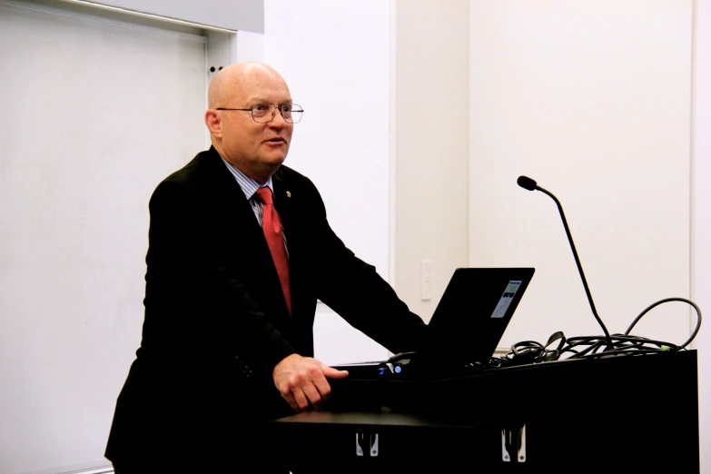 a man standing at a podium while using his laptop