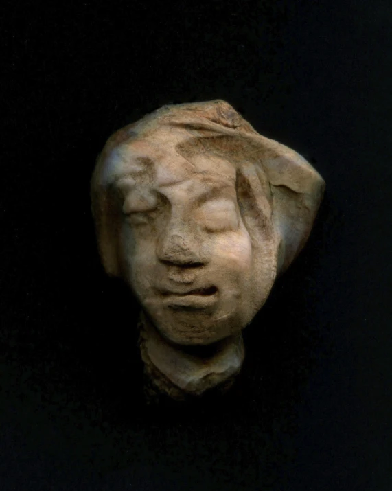 a small face made from wood on a black background