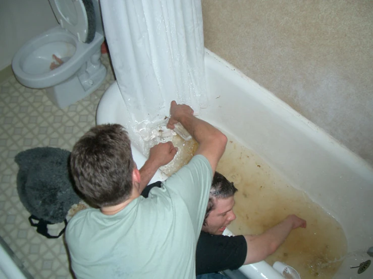 two men fixing toilet paper in a bathroom