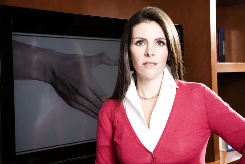 a woman wearing a red shirt is standing in front of a television