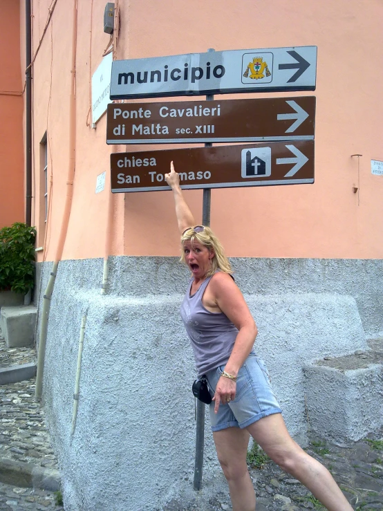 woman leaning on a sign pointing in to the side