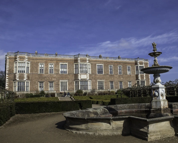 a large brick building with two fountains and a statue in front