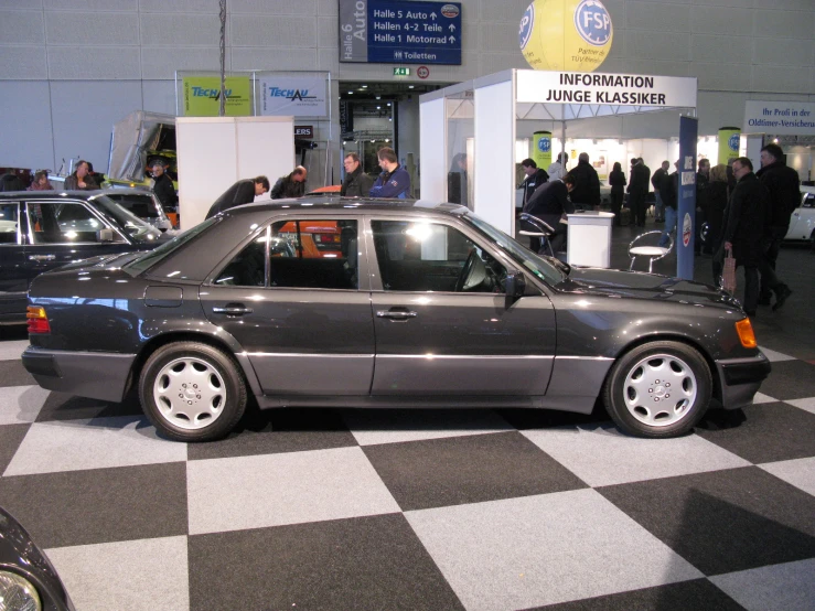 the gray car is parked on the checkerboard floor