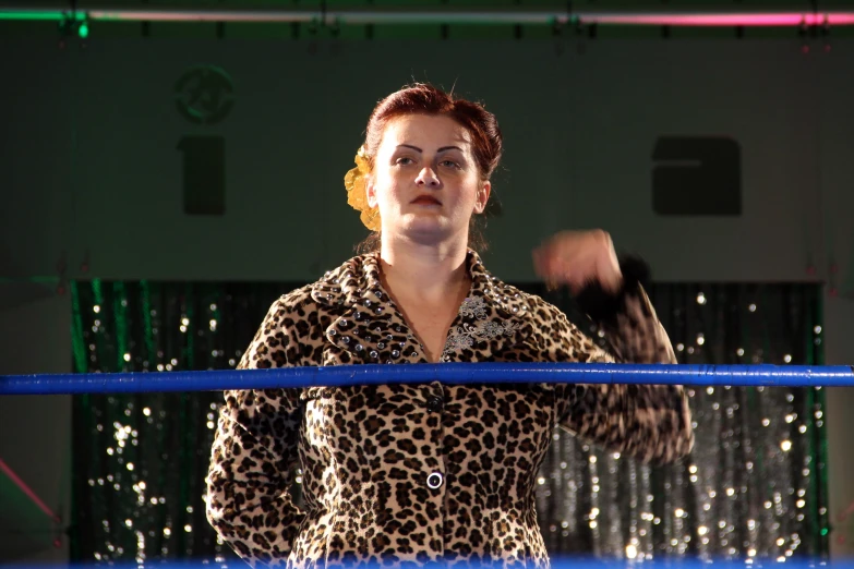 a woman with short red hair stands in an arena, surrounded by blue and green ring