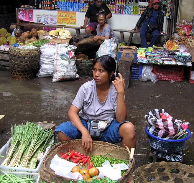 a woman is sitting on the ground talking on her cell phone