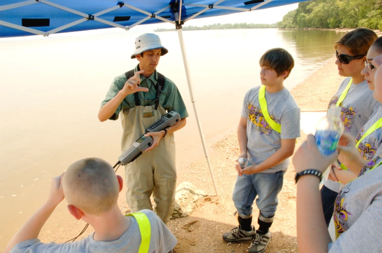 a man standing in front of two boys with a machine gun