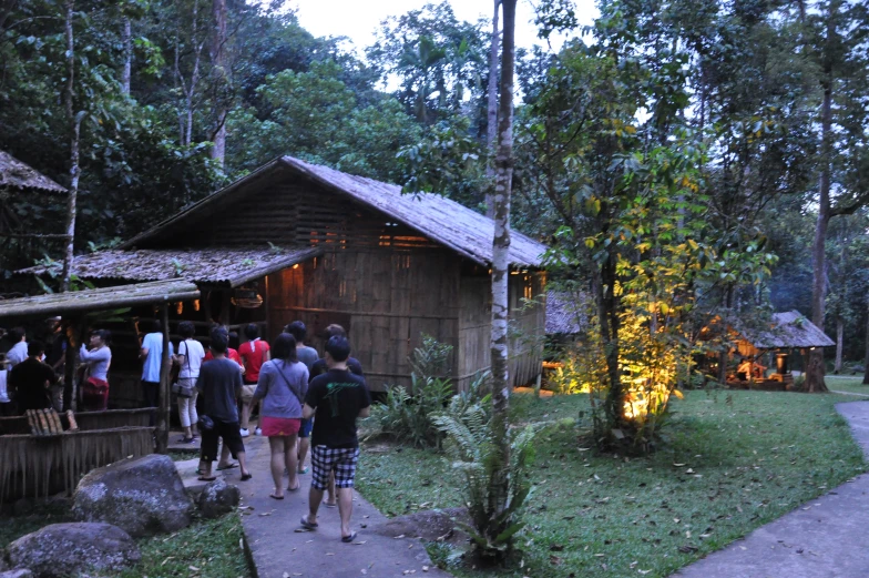many people standing outside a building in the woods