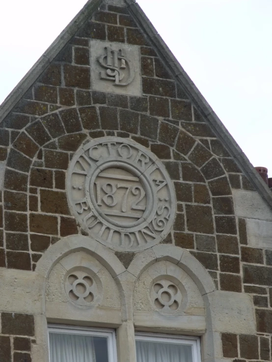 a brick building has two windows and a seal on top