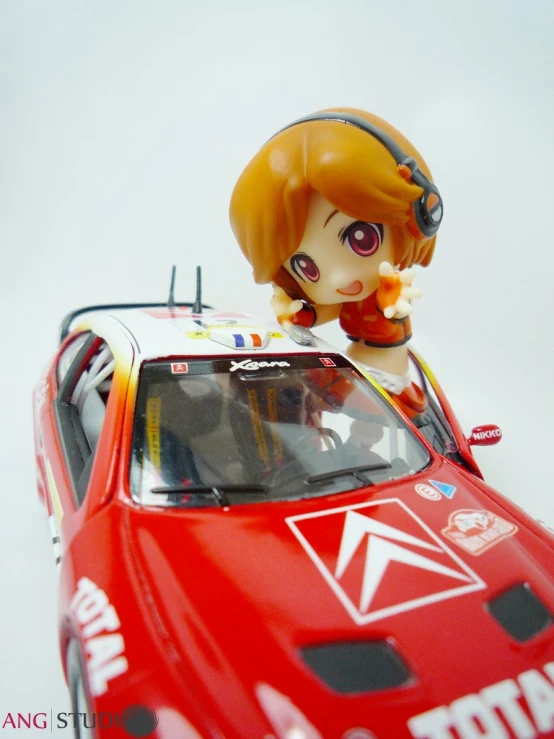 a doll that is on top of a red car