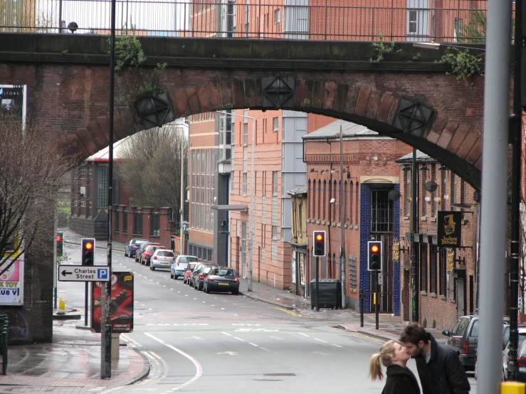 people kissing in the street under an arched stone bridge