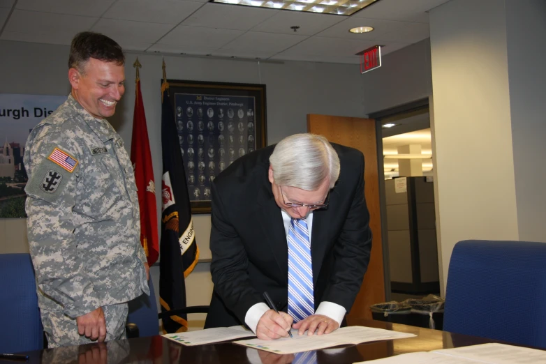 a man signing papers while standing near another soldier