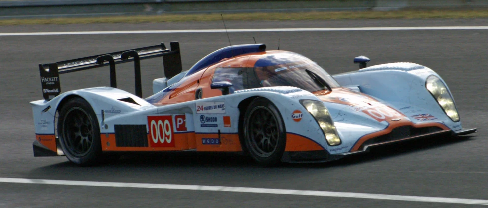 a race car driving around a track in the sunlight