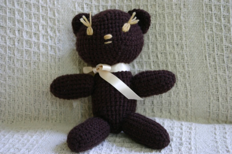 a crocheted brown teddy bear on a white surface
