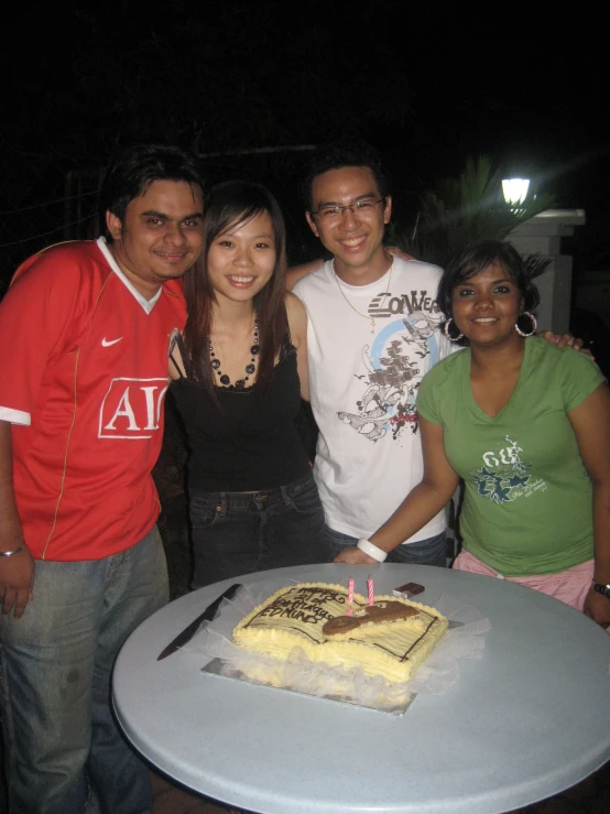 a group of people standing by a cake