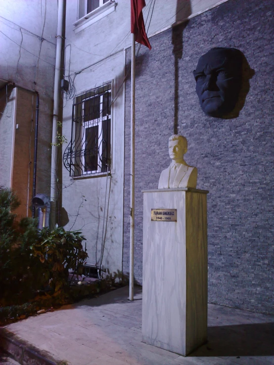 a statue of a man wearing a hat stands outside of a building