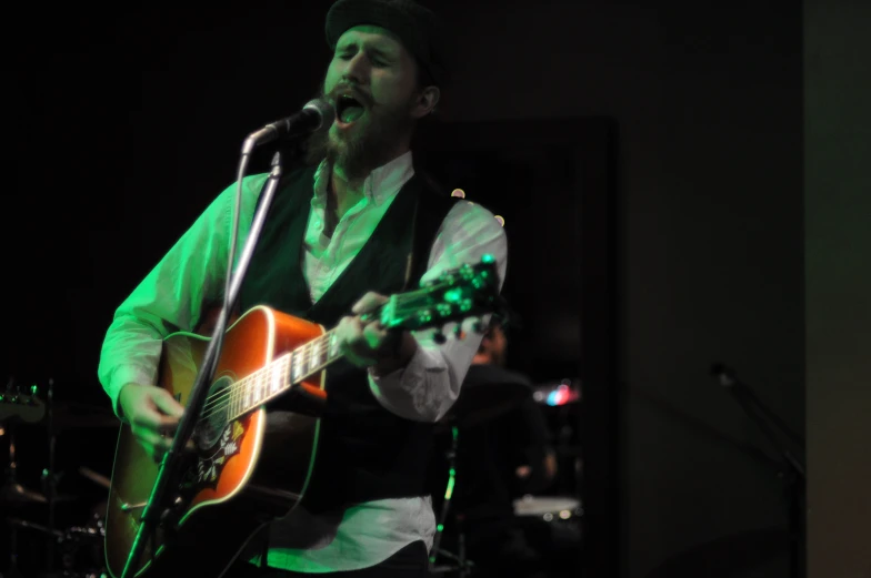 a man with an acoustic guitar and microphone