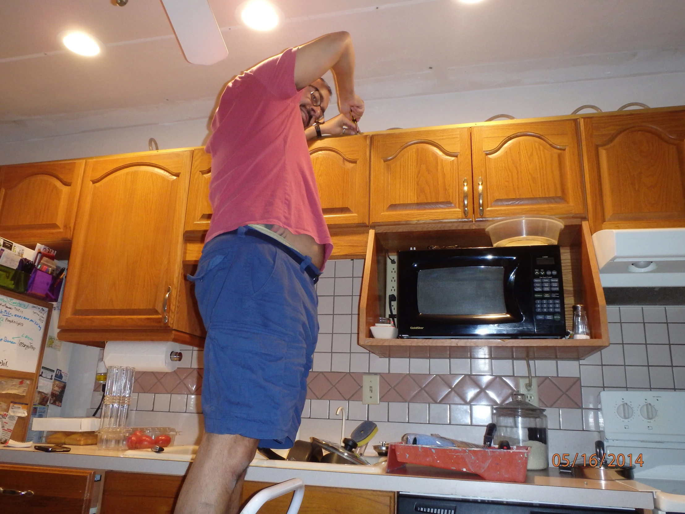 a man is reaching high into the ceiling of a kitchen