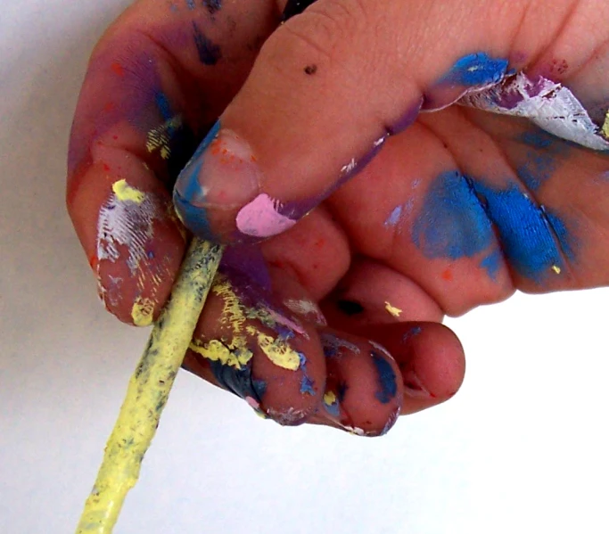 a child's hand holding a pencil with colorful crayons on it