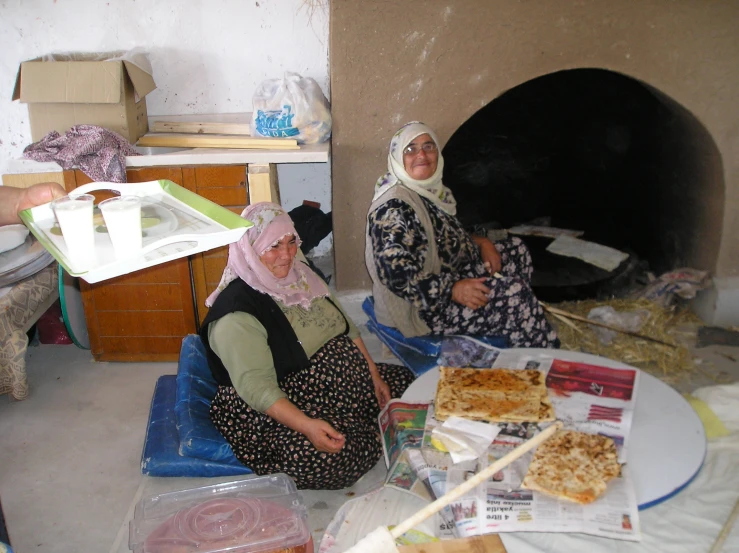 two women sit near a fire place and look at the camera