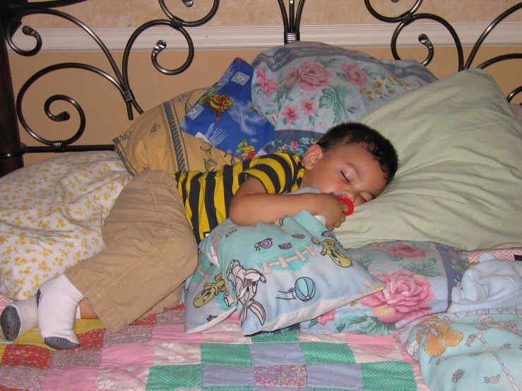 a child is sleeping in his bed with pillows and blankets