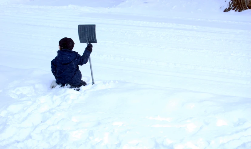 a  holding up a giant shovel in the snow