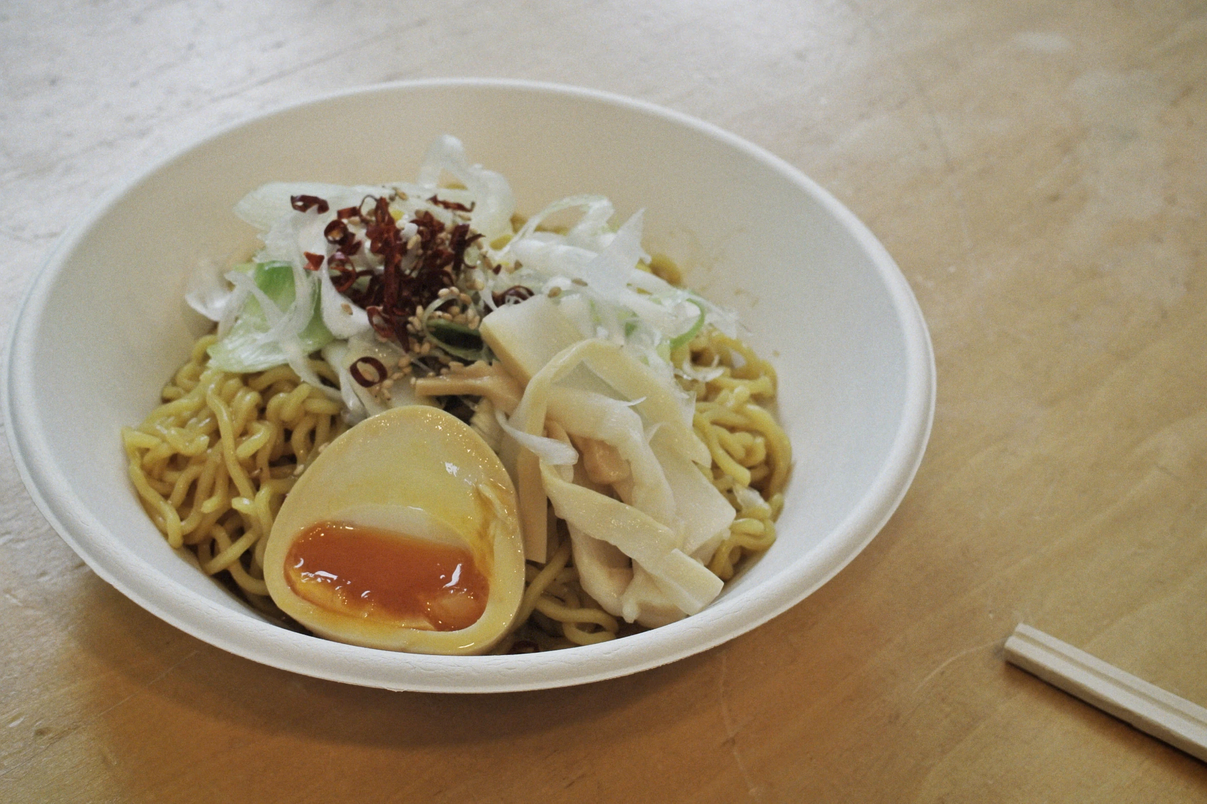 a white bowl with noodles and some condiments in it