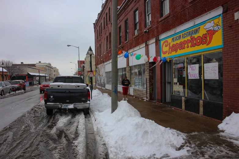 the car is driving down the snow - covered street