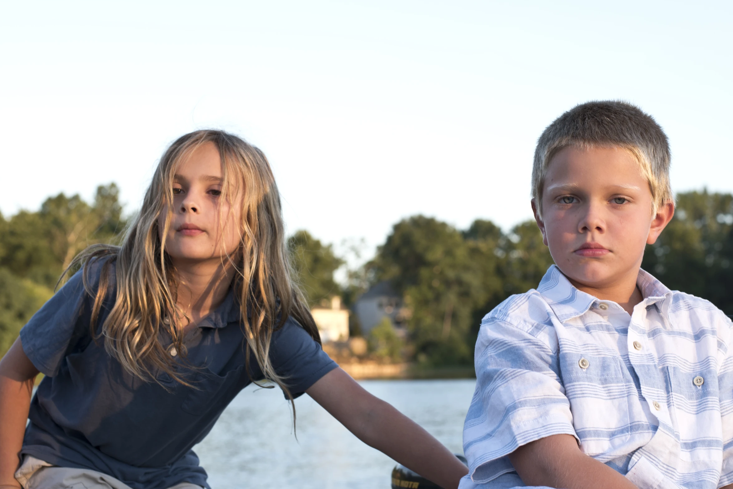 two children sitting next to each other looking up at the camera