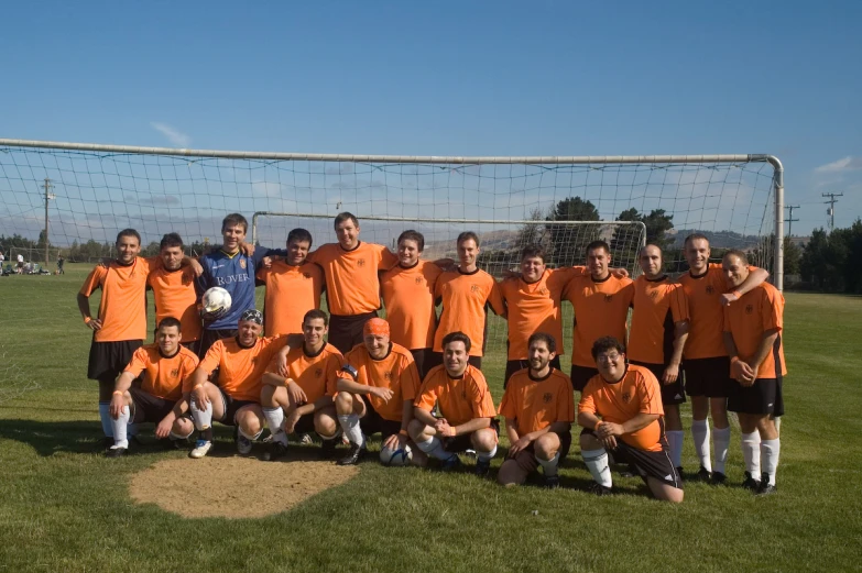 many people are posing for a group pograph in front of a soccer goal