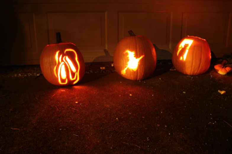 three pumpkins decorated with carved faces in front of a house